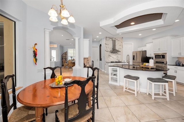 1033 Tuscany Dr, Trinity, FL 34655 - dining room with arched walkways, light tile patterned floors, a chandelier, a tray ceiling, and ornate columns