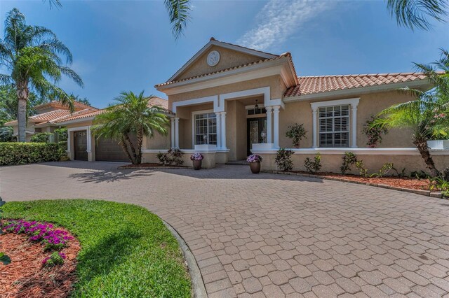 1033 Tuscany Dr, Trinity, FL 34655 - view of front of property featuring an attached garage, curved driveway, a tile roof, and stucco siding