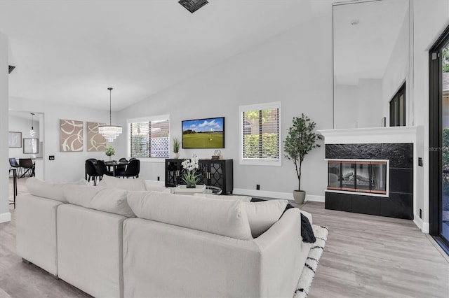 3047 Bolt Dr, Palm Harbor, FL 34685 - living area featuring wood finished floors, visible vents, a tiled fireplace, high vaulted ceiling, and a notable chandelier