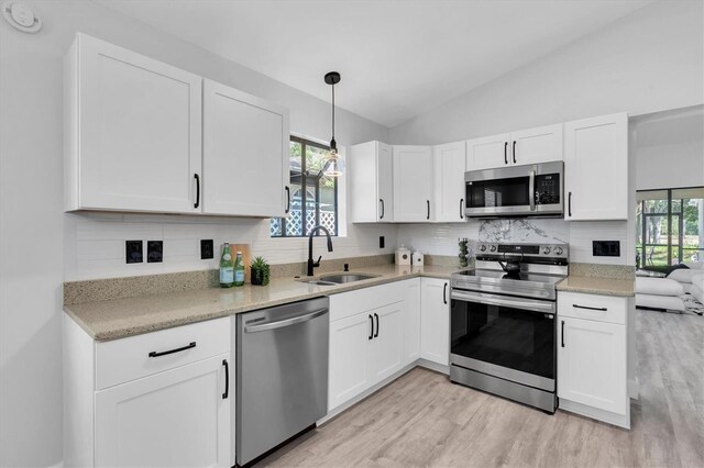 3047 Bolt Dr, Palm Harbor, FL 34685 - kitchen with a sink, decorative backsplash, white cabinetry, light wood-style flooring, and appliances with stainless steel finishes