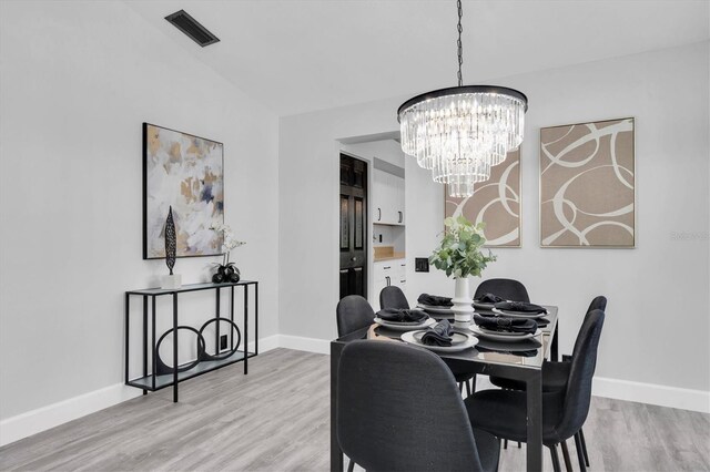 3047 Bolt Dr, Palm Harbor, FL 34685 - dining area with baseboards, a notable chandelier, visible vents, and light wood-type flooring