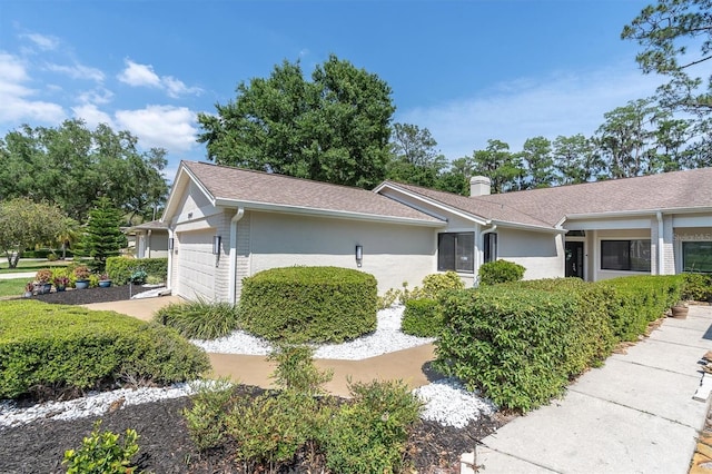 3047 Bolt Dr, Palm Harbor, FL 34685 - view of side of property with a chimney, an attached garage, and stucco siding