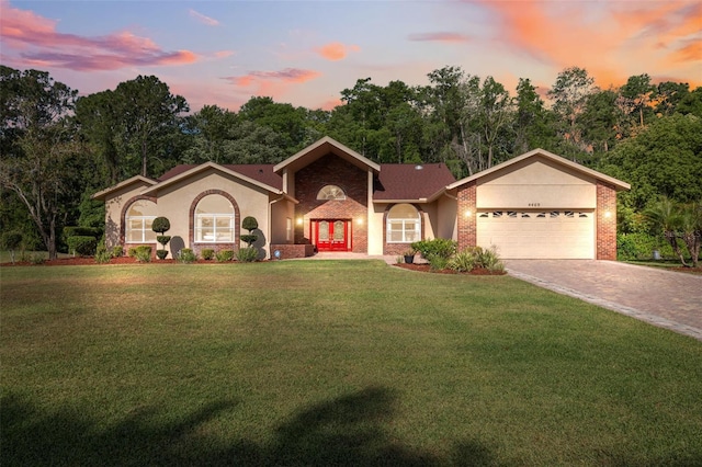 view of front of house featuring a garage, a lawn, driveway, stucco siding, and french doors