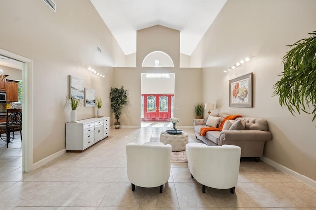 living room with light tile patterned flooring, visible vents, high vaulted ceiling, and baseboards