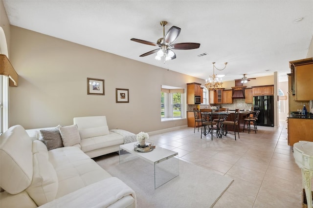 living area featuring light tile patterned flooring, visible vents, baseboards, and ceiling fan with notable chandelier