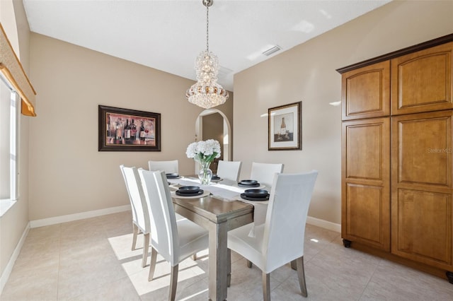 dining area with light tile patterned floors, a notable chandelier, visible vents, and baseboards