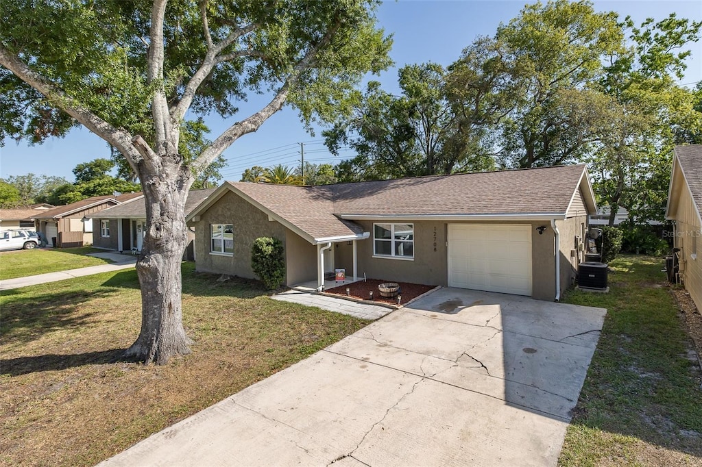 single story home with driveway, a front yard, stucco siding, central AC, and a garage