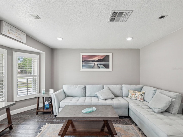 living area featuring a textured ceiling, visible vents, baseboards, recessed lighting, and dark wood-type flooring