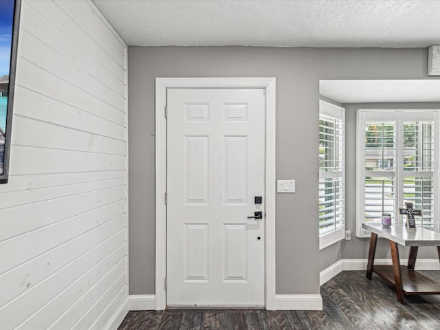 entryway with a textured ceiling, dark wood-style floors, and baseboards