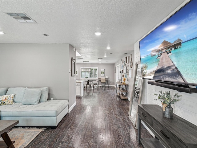 living room featuring recessed lighting, dark wood-style flooring, baseboards, visible vents, and a textured ceiling