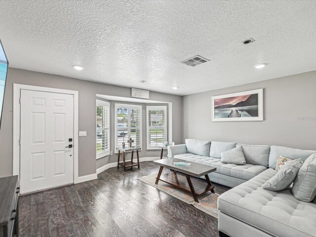 living area with dark wood finished floors, visible vents, a textured ceiling, and recessed lighting