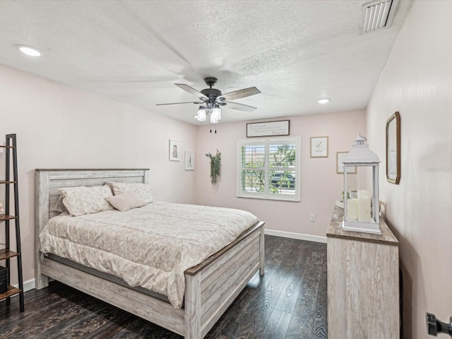 bedroom featuring dark wood finished floors, ceiling fan, baseboards, visible vents, and a textured ceiling