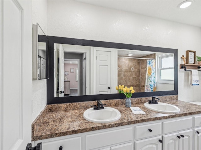 bathroom featuring double vanity, a sink, and a textured wall