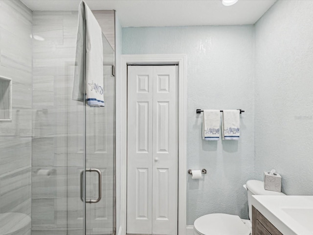 full bathroom with vanity, toilet, a shower stall, and a closet