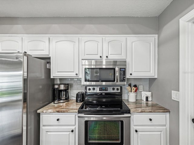 kitchen featuring white cabinets, appliances with stainless steel finishes, and tasteful backsplash