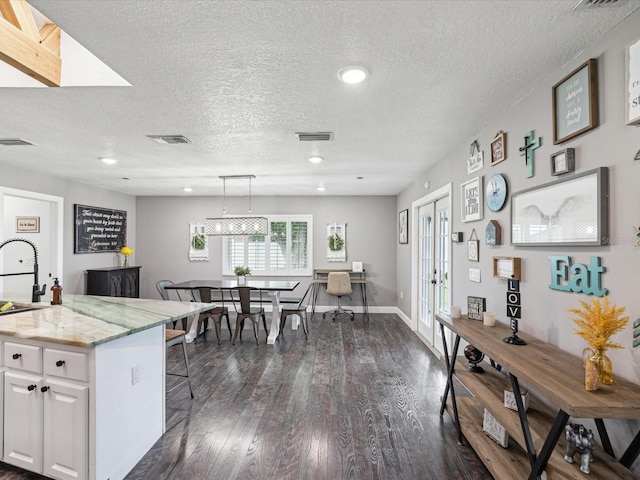 kitchen with visible vents, a kitchen bar, white cabinets, and dark wood-style floors
