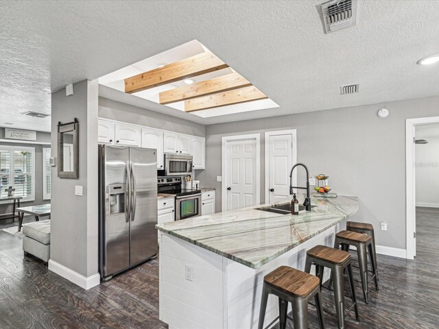 kitchen featuring appliances with stainless steel finishes, a sink, baseboards, visible vents, and a textured ceiling
