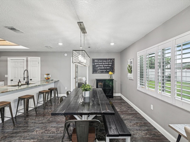 dining area featuring baseboards, a fireplace, dark wood-style floors, visible vents, and a textured ceiling