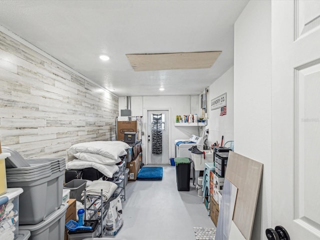 bedroom with an accent wall, wooden walls, washer and dryer, recessed lighting, and access to outside