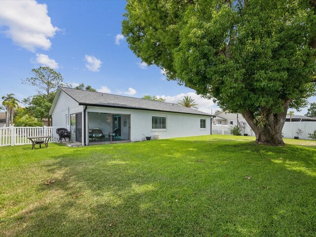 rear view of property featuring a yard, stucco siding, and fence