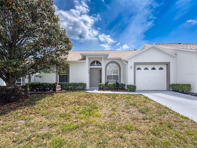 view of front of property with an attached garage, stucco siding, concrete driveway, and a front yard