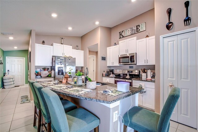 680 Argyll Dr, Spring Hill, FL 34609 - kitchen with white cabinets, a kitchen breakfast bar, visible vents, appliances with stainless steel finishes, and light tile patterned floors