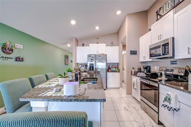 680 Argyll Dr, Spring Hill, FL 34609 - kitchen with a sink, a kitchen island with sink, white cabinetry, lofted ceiling, and appliances with stainless steel finishes