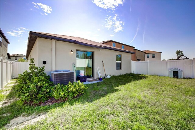 680 Argyll Dr, Spring Hill, FL 34609 - back of property featuring a lawn, central AC unit, a fenced backyard, and stucco siding