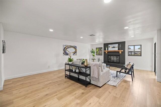 living room with a fireplace, recessed lighting, visible vents, and light wood-style flooring