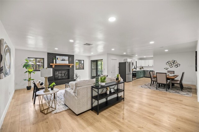 living room with recessed lighting, visible vents, baseboards, light wood-style flooring, and a brick fireplace