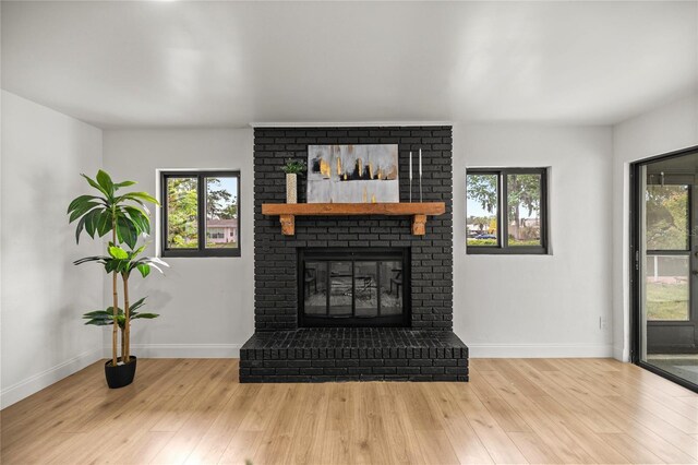 living room featuring baseboards, a brick fireplace, wood finished floors, and a wealth of natural light