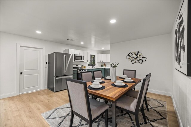 dining room featuring baseboards, recessed lighting, and light wood-style floors