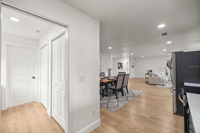 hall with recessed lighting, visible vents, and light wood-style flooring
