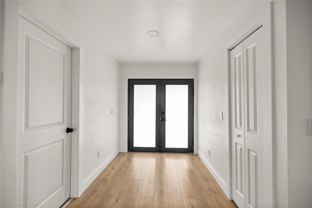entryway with light wood-type flooring, baseboards, and french doors