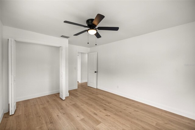 unfurnished bedroom featuring light wood-style flooring, baseboards, visible vents, a ceiling fan, and a closet