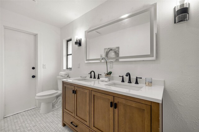 bathroom with double vanity, toilet, and a sink