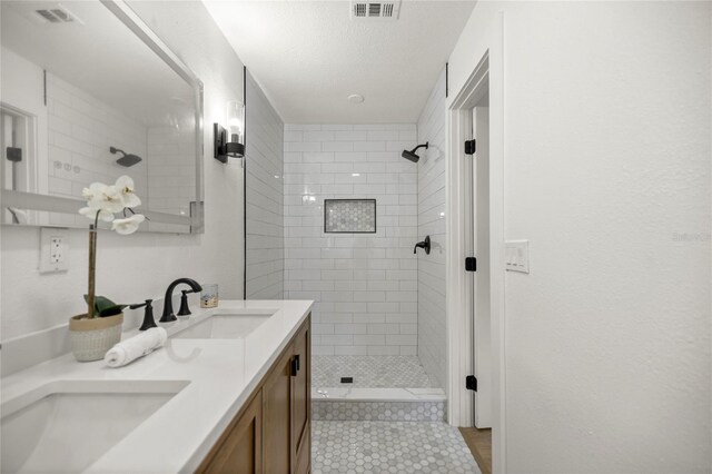 bathroom with tile patterned floors, a sink, a shower stall, and double vanity