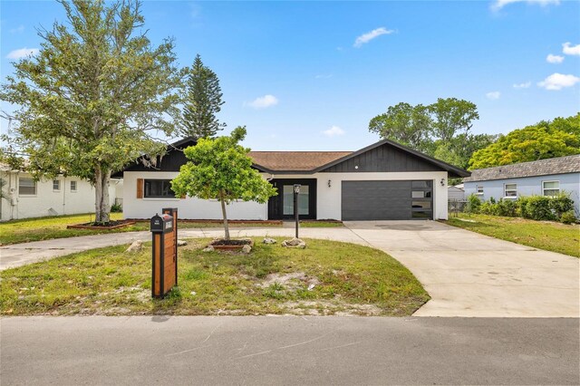 ranch-style home featuring concrete driveway, a front yard, and a garage