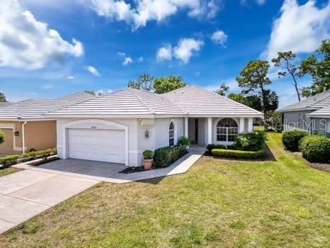 9237 Penelope Dr, Weeki Wachee, FL 34613 - single story home featuring a tile roof, an attached garage, a front lawn, and concrete driveway