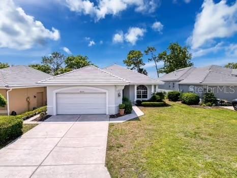 9237 Penelope Dr, Weeki Wachee, FL 34613 - ranch-style home featuring a front lawn, stucco siding, an attached garage, a tile roof, and concrete driveway
