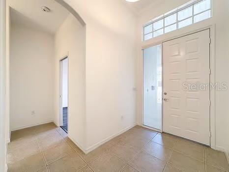 9237 Penelope Dr, Weeki Wachee, FL 34613 - entrance foyer featuring baseboards, arched walkways, and light tile patterned floors