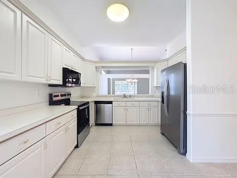 9237 Penelope Dr, Weeki Wachee, FL 34613 - kitchen with a sink, light tile patterned flooring, an inviting chandelier, stainless steel appliances, and light countertops