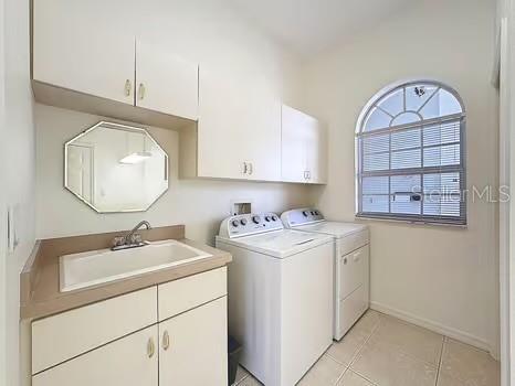 9237 Penelope Dr, Weeki Wachee, FL 34613 - washroom with a sink, separate washer and dryer, light tile patterned floors, cabinet space, and baseboards