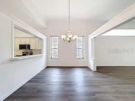 9237 Penelope Dr, Weeki Wachee, FL 34613 - unfurnished dining area with dark wood finished floors, baseboards, and a notable chandelier