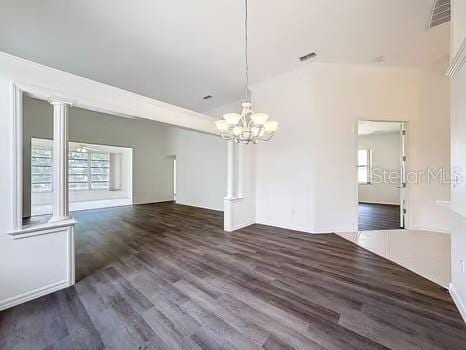 9237 Penelope Dr, Weeki Wachee, FL 34613 - unfurnished dining area featuring an inviting chandelier, visible vents, wood finished floors, and decorative columns