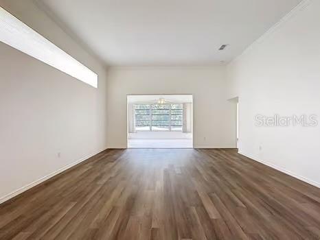 9237 Penelope Dr, Weeki Wachee, FL 34613 - spare room featuring baseboards and dark wood-style flooring