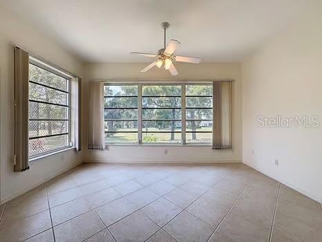 9237 Penelope Dr, Weeki Wachee, FL 34613 - empty room featuring a ceiling fan, tile patterned flooring, and a healthy amount of sunlight