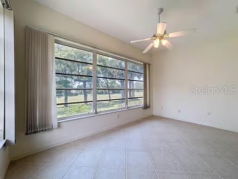 9237 Penelope Dr, Weeki Wachee, FL 34613 - empty room with plenty of natural light, a ceiling fan, and light tile patterned floors