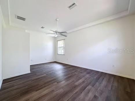 9237 Penelope Dr, Weeki Wachee, FL 34613 - empty room with ceiling fan, visible vents, baseboards, and dark wood-style flooring