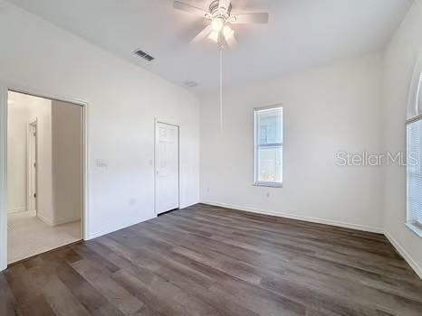9237 Penelope Dr, Weeki Wachee, FL 34613 - unfurnished bedroom with wood finished floors, visible vents, ceiling fan, and multiple windows